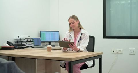 Female clinician reviewing patient chart on tablet in minimalist clinic office