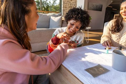 Friends painting nails together at-home manicure party in sunlit cozy living room