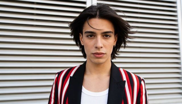 Confident young male model wearing red black striped blazer and hoop nose-ring