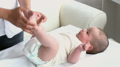 Mother Gently Massaging Infant's Feet at Home