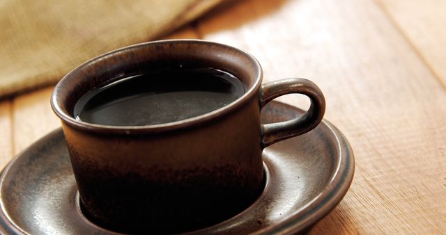 A close-up view of a steaming cup of coffee in a ceramic mug on a wooden table, with copy space. The warmth of the beverage is inviting for a cozy break or morning start.