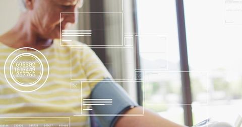 Senior woman checking blood pressure at home wearing cuff with telehealth hud overlays