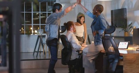 Diverse team celebrating success in modern office at night