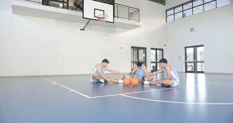 Team practice: young basketball players stretching on indoor court