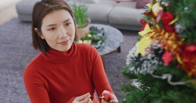 Image of happy asian woman decorating christmas tree at home - Download Free Stock Photos Pikwizard.com