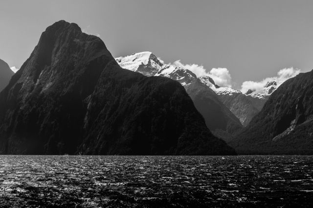 Black and white landscape showcasing a serene mountain with snow-capped peaks and a tranquil lake, capturing the beauty of nature. Ideal for travel blogs, nature documentaries, office decor, and inspirational posters.