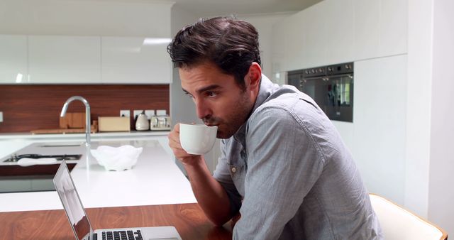 Young Man Drinking Coffee While Working at Home in Modern Kitchen - Download Free Stock Images Pikwizard.com