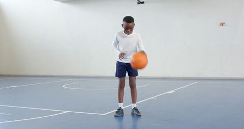 Young boy practicing basketball dribbling in indoor sports gym