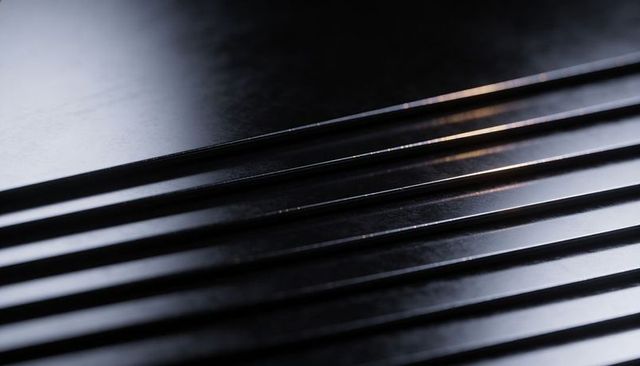 Reflecting grooved black panel with polished ridged texture and specular highlights
