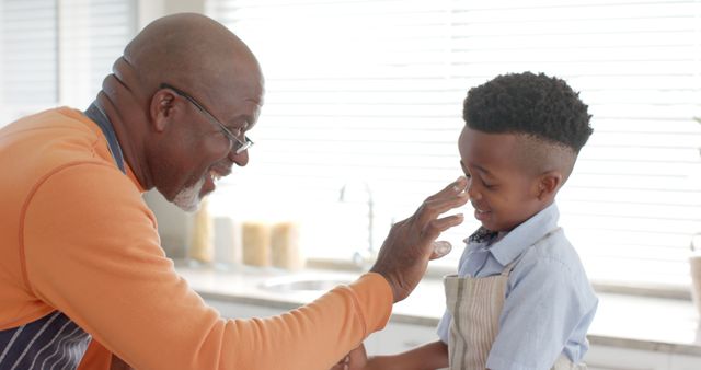 Grandfather Playfully Touching Grandson's Nose in Kitchen - Download Free Stock Images Pikwizard.com