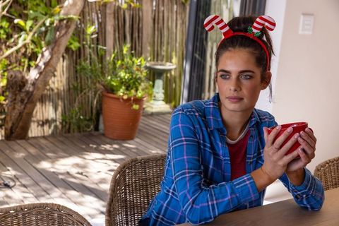 Woman relaxing with coffee on rustic patio in festive headband