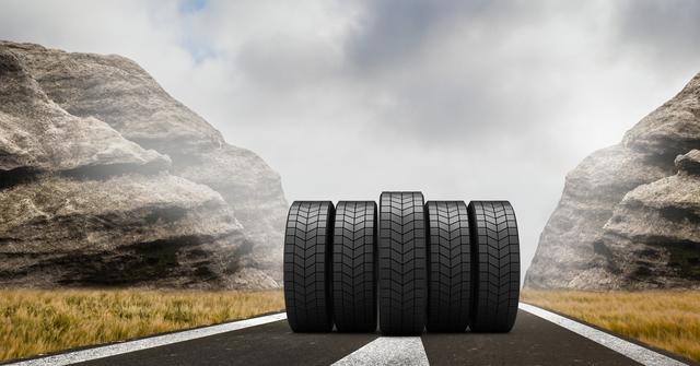 Car tires standing in middle of empty road flanked by rocky formations and cloudy sky offer versatility and resilience themes. Ideal for automotive advertisements, transportation services, travel-themed promotions, or rugged outdoor ventures showcasing durability.