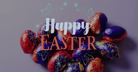 Happy easter foil-wrapped chocolate eggs glinting on mauve-gray tabletop with teal doodles