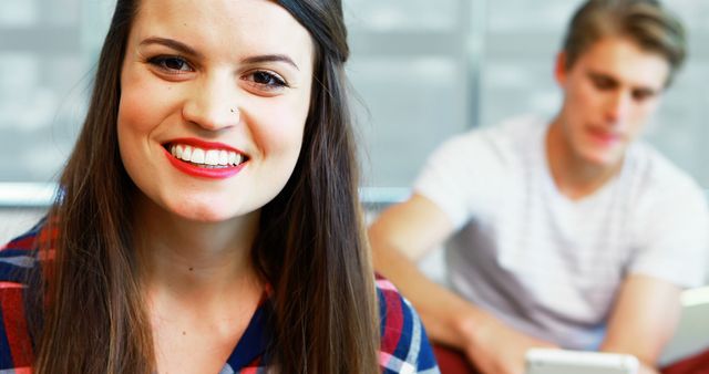 Smiling Young Woman With Friend Using Tablet in Background - Download Free Stock Images Pikwizard.com