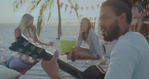Playing Guitar on Beach with Friends Enjoying Summer Vibes