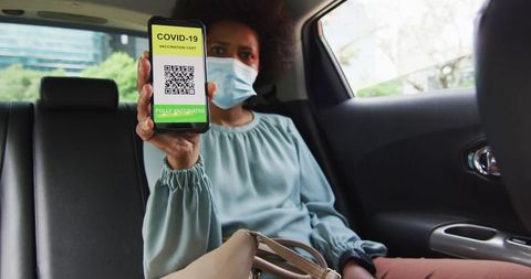 Businesswoman showing covid-19 vaccination certificate on smartphone