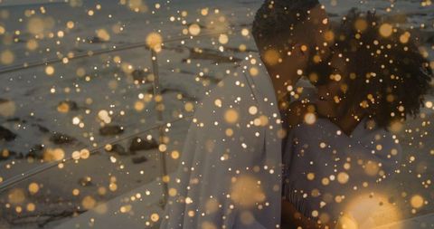 Black couple embracing on twilight beach wrapped in shawl with warm golden bokeh, intimate mood