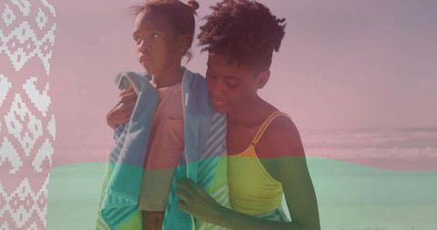 Wrapping daughter in turquoise-striped towel on pastel beach shore warm caregiver moment