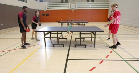 Diverse group energetically playing table tennis in gym