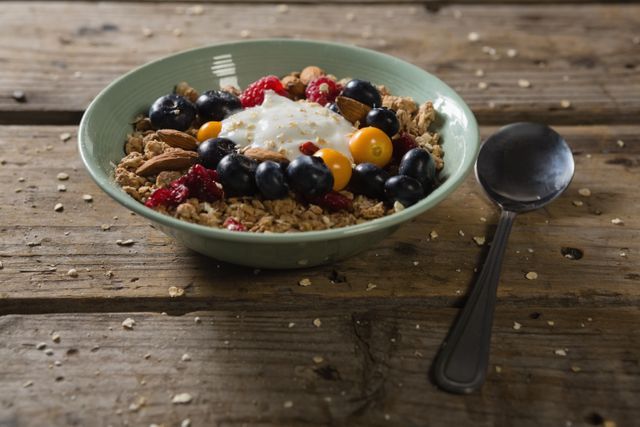 Bowl of breakfast cereals with spoon on wooden table