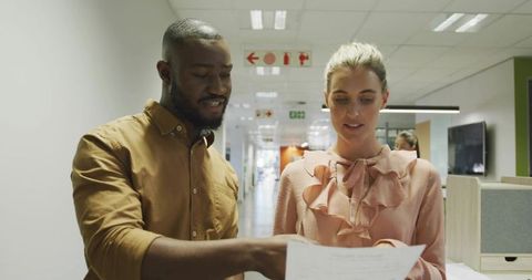 Colleagues reviewing documents in office hallway with signage