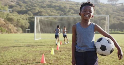 Smiling Boy Holding Soccer Ball at Outdoor Practice Field