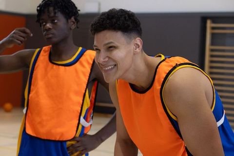 Diverse Male Athletes Practicing Basketball in School Gym