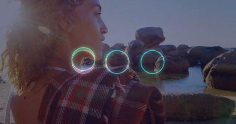 Woman relaxing by boulder-lined shoreline at sunset