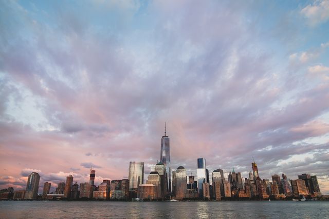 Skyscrapers of New York City under a colorful sunset sky with dramatic clouds. Ideal for travel brochures, blog posts about urban life or architecture, and illustrative purposes for articles focusing on New York City.