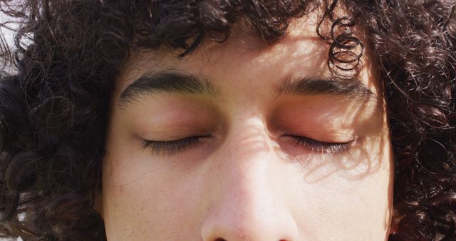 Closeup captures a person with closed eyes, evoking a sense of relaxation and inner peace. Can be used to depict mindfulness, meditation, stress relief, or promoting self-care and well-being.