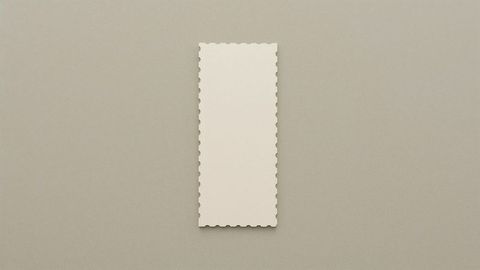 Blank scalloped-edge paper on gray taupe surface