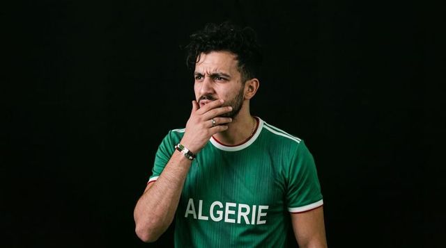 Algerian fan holding hand to mouth showing concern wearing green algerie jersey