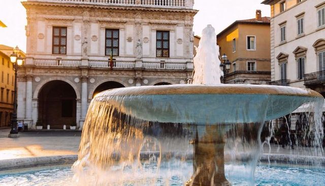 Golden light bathing classical fountain with cascading water in historic plaza