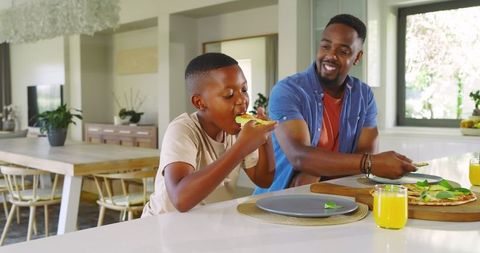 Father and Son Enjoying Pizza in Modern Kitchen Interior