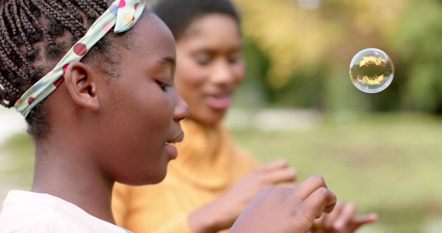 Happy african american mother and daughter blowing bubbles in sunny garden - Download Free Stock Photos Pikwizard.com