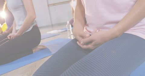 Practicing Kneeling Meditation in Group Wellness Class Showing Hands on Lap and Striped Leggings