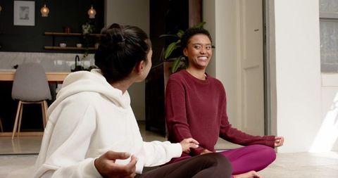 Female Friends Meditating Together in Sunlit Modern Home Interior