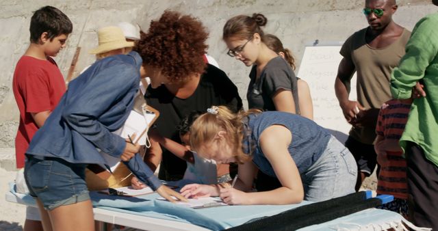 Group of young diverse volunteers signing registration forms during a beach cleanup event. Ideal for illustrating community engagement, environmental activities, and teamwork. Useful for promoting volunteer efforts, environmental causes, and event coordination.