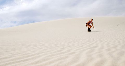 Adventurous Woman Sandboarding on Expansive Desert Dunes - Download Free Stock Images Pikwizard.com
