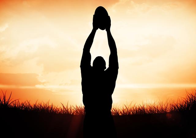 Silhouette of a man catching a rugby ball against a colorful sunset sky. Suitable for use in sports advertisements, fitness campaigns, outdoor activity promotions, motivational posters, and inspirational quotes. The dramatic sky and backlighting create a powerful and dynamic visual impact, perfect for emphasizing themes of determination and athleticism.