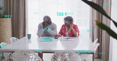Senior couple reviewing finances in cozy dining space, ensuring comfort and stability