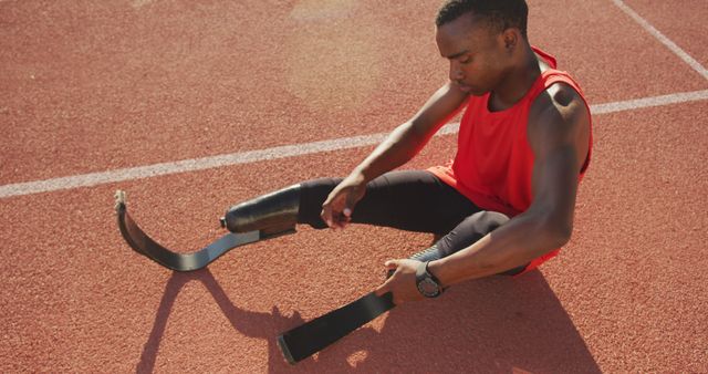 Paralympic sprinter adjusting prosthetic leg before race on track - Download Free Stock Images Pikwizard.com