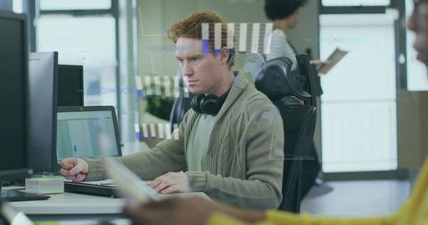 Focused Man with Headphones Multitasking at Modern Workspace