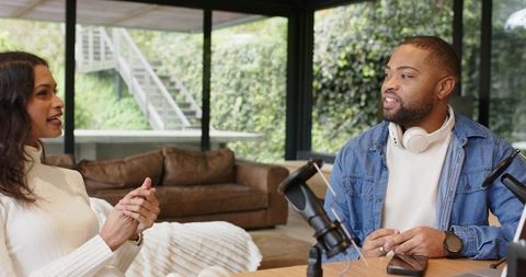 Recording relaxed podcast interview with diverse cohosts in modern living room studio