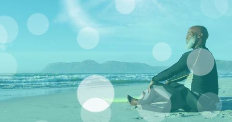 Senior Surfer Meditating on Tranquil Beach with Light Spots