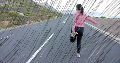 Young woman stretching on mountain road in athletic gear