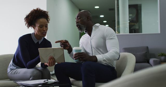 Diverse male and female business colleagues talking, woman holding digital tablet in office. business professionals and working in busy modern office.