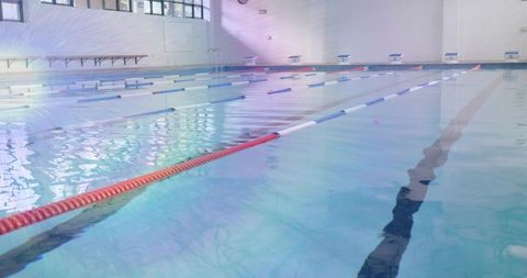 Sunlit indoor swimming pool with lane ropes for professional training
