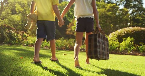Children Walking in Sunlit Garden Holding Teddy Bear and Suitcase - Download Free Stock Images Pikwizard.com