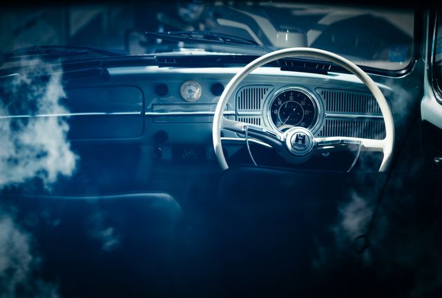 This image captures the interior of a classic vintage car, featuring the steering wheel and dashboard. Ideal for use in automotive blogs, retro vehicle advertisements, historical car collections, and nostalgia-themed presentations. Perfect for illustrating the elegance and design of vintage automobiles.